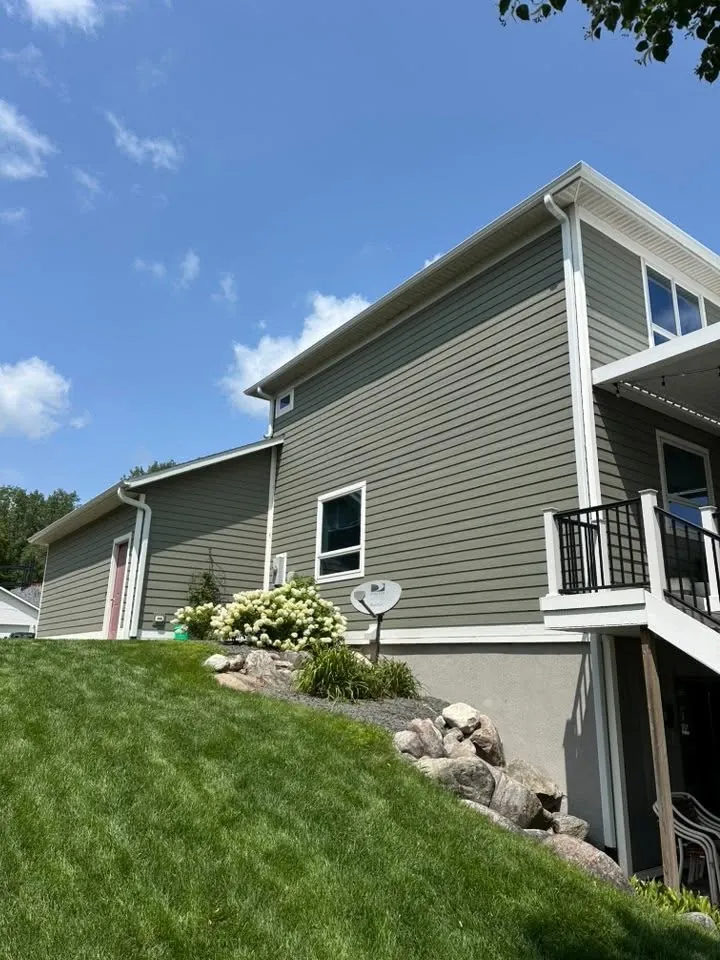 Two-story home in sage green lap siding with white trim and a black rail deck